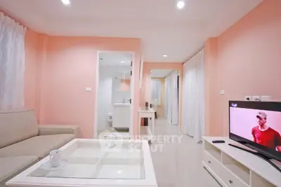 Modern living room with peach walls and sleek furniture, featuring a TV and coffee table.