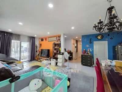 Spacious living room with modern decor and ample natural light, featuring a cozy play area and elegant chandelier.