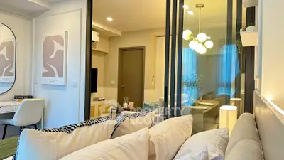 Modern living room with stylish decor and glass partition, featuring cozy seating and elegant lighting.