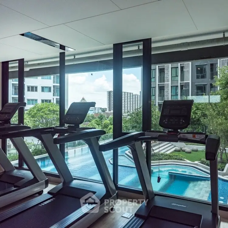 Modern gym with treadmills overlooking a luxurious pool and scenic view.