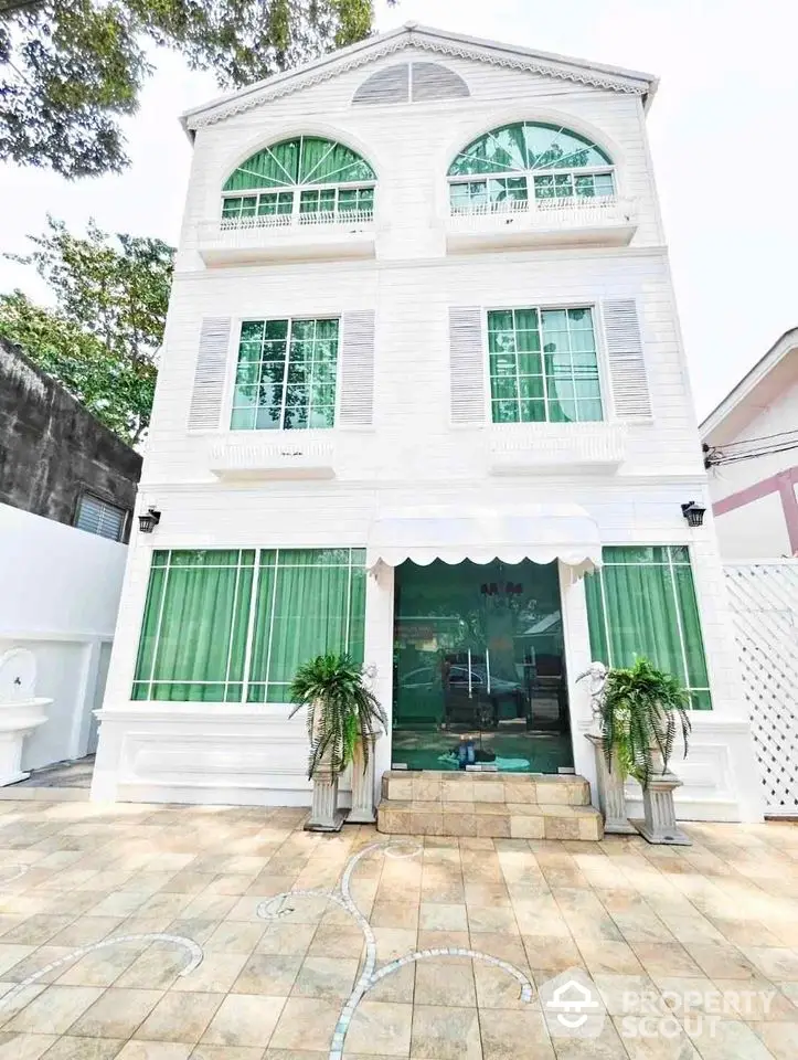 Stunning three-story white building with green accents and elegant entrance