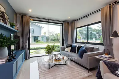 Modern living room with large windows and stylish decor overlooking a scenic garden view.