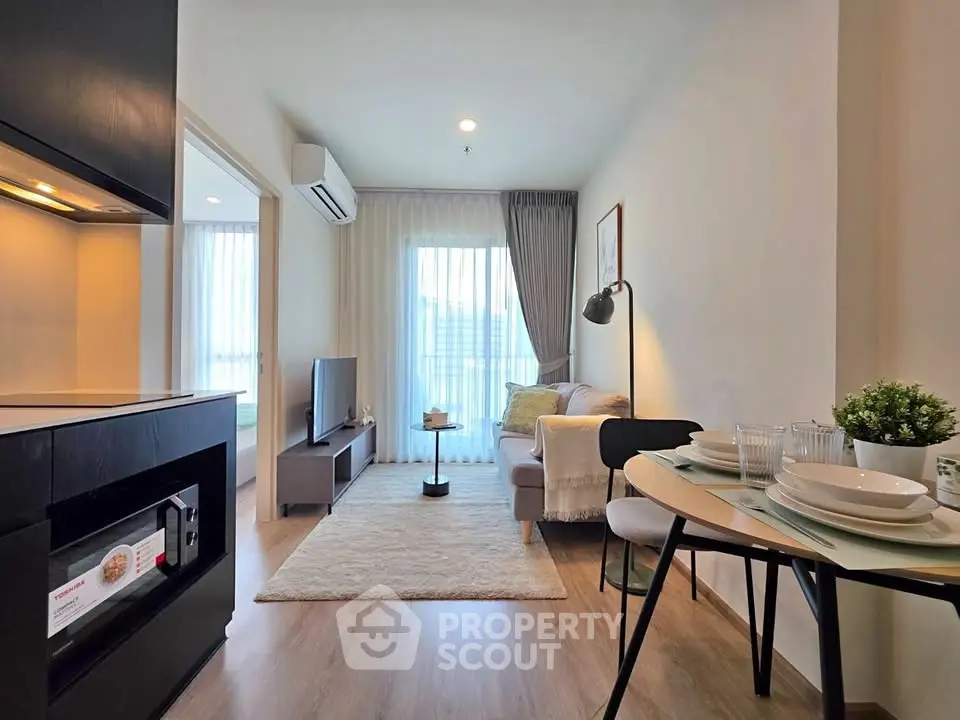 Modern living room with cozy decor and open kitchen layout in a stylish apartment.