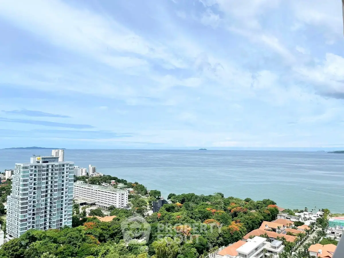 Stunning ocean view from high-rise building overlooking lush greenery and coastline.