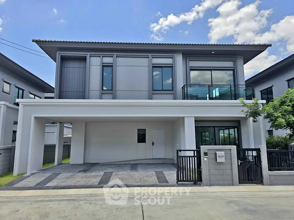 Modern two-story house with sleek design and spacious driveway in a suburban neighborhood.