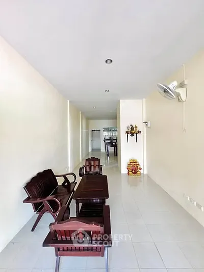 Spacious living area with wooden furniture and bright white tiles