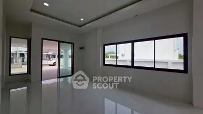 Spacious modern living room with large windows and sleek tile flooring in a contemporary home.