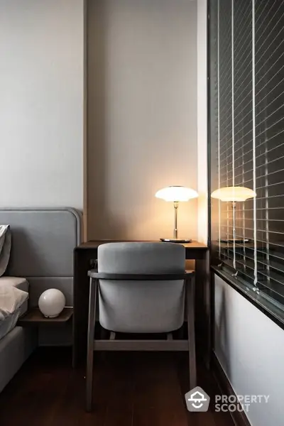 Modern bedroom with stylish desk and lamp beside bed, featuring elegant decor and warm lighting.