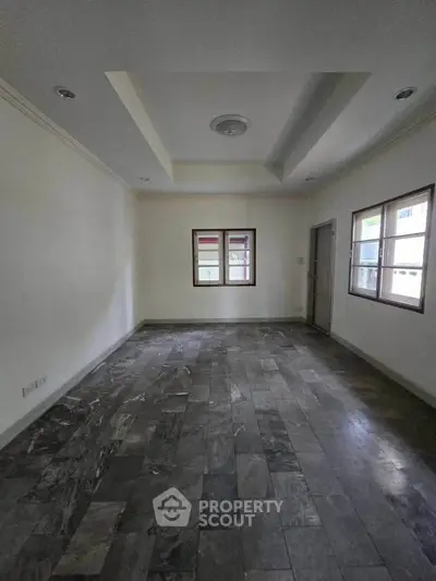 Spacious empty room with tiled flooring and large windows, ideal for customization.