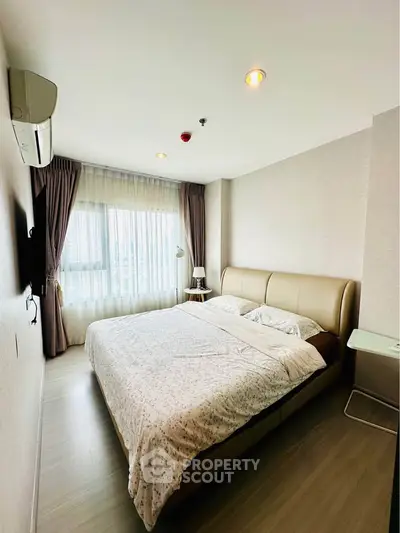 Spacious bedroom with modern decor and large window for natural light