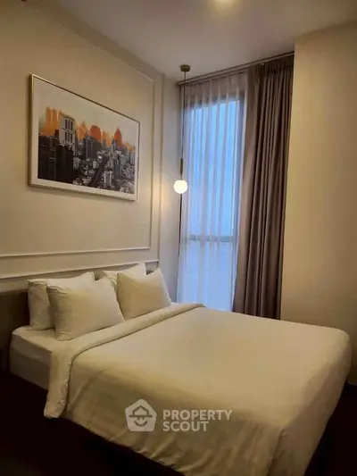 Cozy bedroom with modern decor and large window offering natural light.