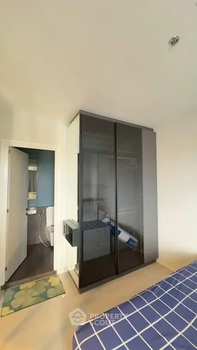 Modern bedroom with sleek wardrobe and ensuite bathroom in stylish apartment.