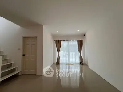 Spacious unfurnished living room with large window and staircase