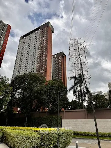 High-rise residential buildings with lush greenery and overcast sky.