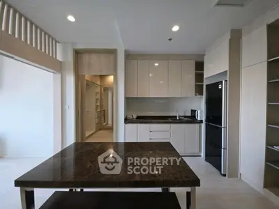 Modern kitchen with sleek cabinetry and marble dining table in open layout apartment.