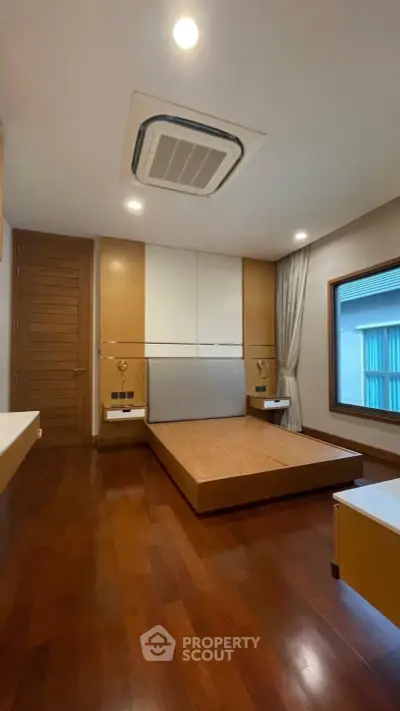 Spacious modern bedroom with wooden flooring and minimalist design