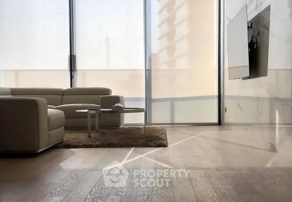 Modern living room with sleek furniture and large windows offering natural light.