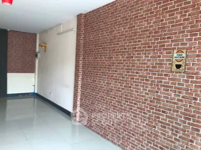 Spacious interior with brick accent wall and glossy flooring, ideal for creative office or retail space.