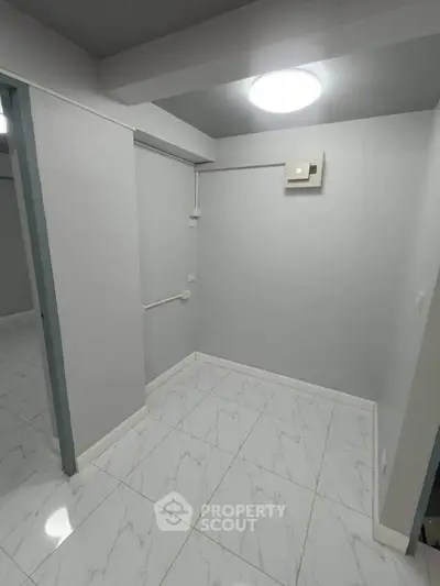 Minimalist interior space with white tiled flooring and neutral walls, ideal for versatile use.