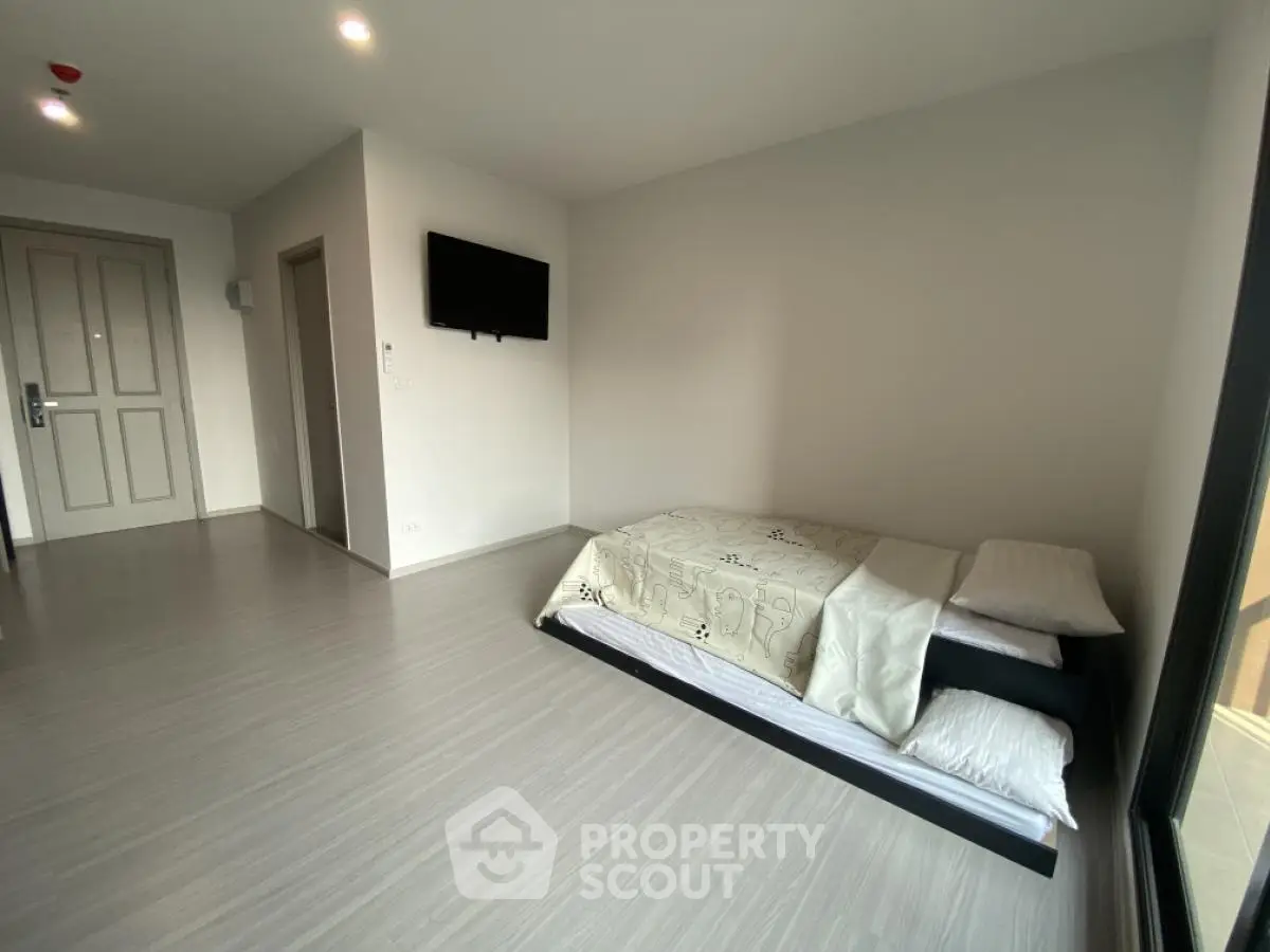 Minimalist bedroom with floor mattress and wall-mounted TV in modern apartment