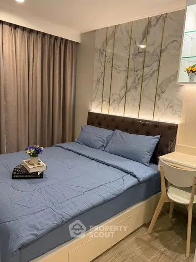 Modern bedroom with elegant marble accent wall and cozy blue bedding