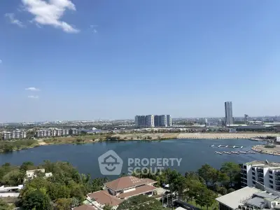 Stunning cityscape view with serene lake and modern high-rise buildings under clear blue sky.