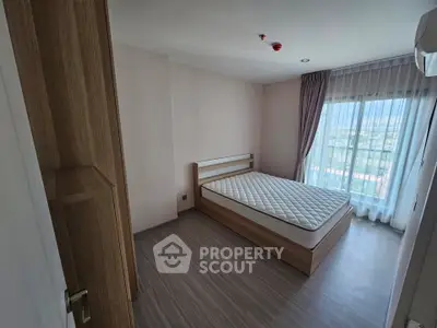 Spacious bedroom with large window and modern wooden furniture