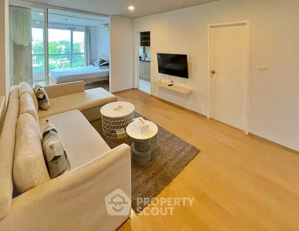 Spacious modern living room with open layout and natural light, featuring cozy seating and sleek TV setup.