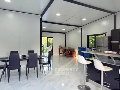 Modern open-plan kitchen and dining area with sleek furniture and bright lighting.