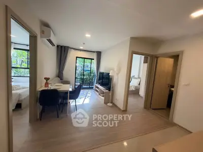 Modern apartment interior with open living and dining area, featuring large windows and natural light.