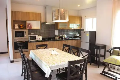 Modern kitchen with dining area featuring wooden cabinets and stainless steel appliances.