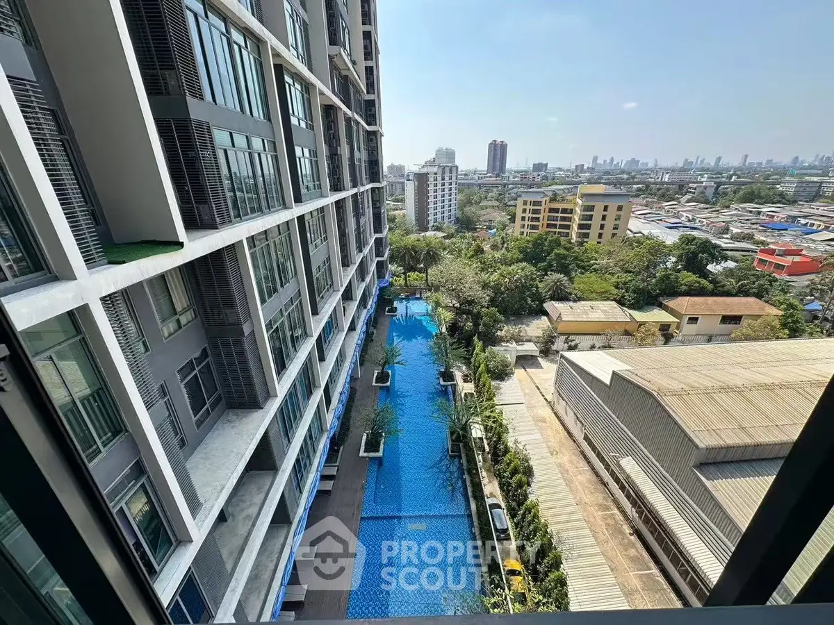 Stunning aerial view of modern building with luxurious pool and cityscape backdrop.