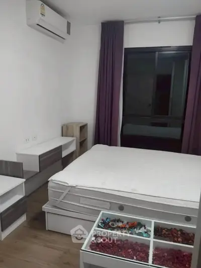 Cozy bedroom with modern furniture and large window, perfect for relaxation.