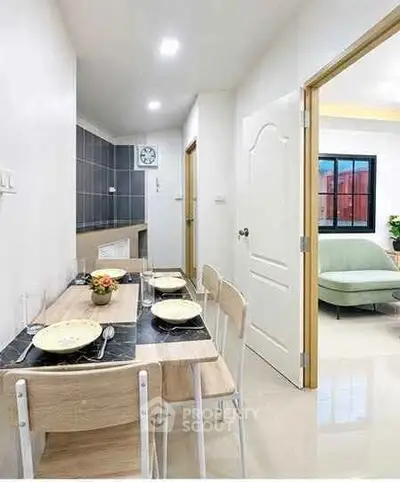 Modern dining area with sleek table set and view into cozy living room