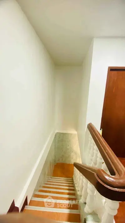 Elegant staircase with wooden handrail and white balusters in a modern home interior.