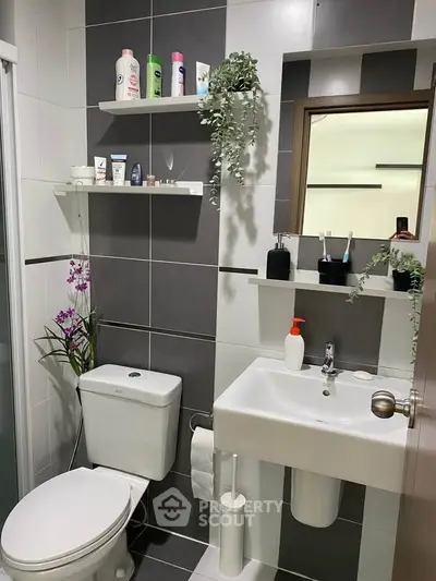 Modern bathroom with sleek design and stylish decor, featuring a compact sink and toilet.
