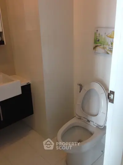 Modern bathroom with sleek fixtures and minimalist design, featuring a stylish sink and toilet.