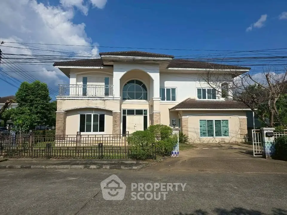 Elegant two-story house with spacious driveway and lush greenery under a clear blue sky.