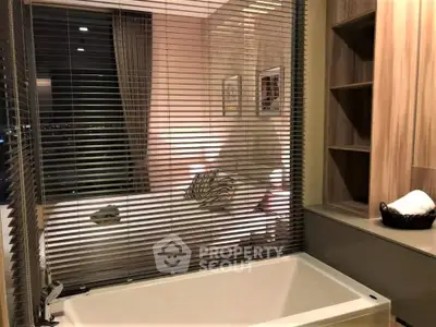 Luxurious bathroom with modern bathtub and stylish blinds overlooking a cozy bedroom.