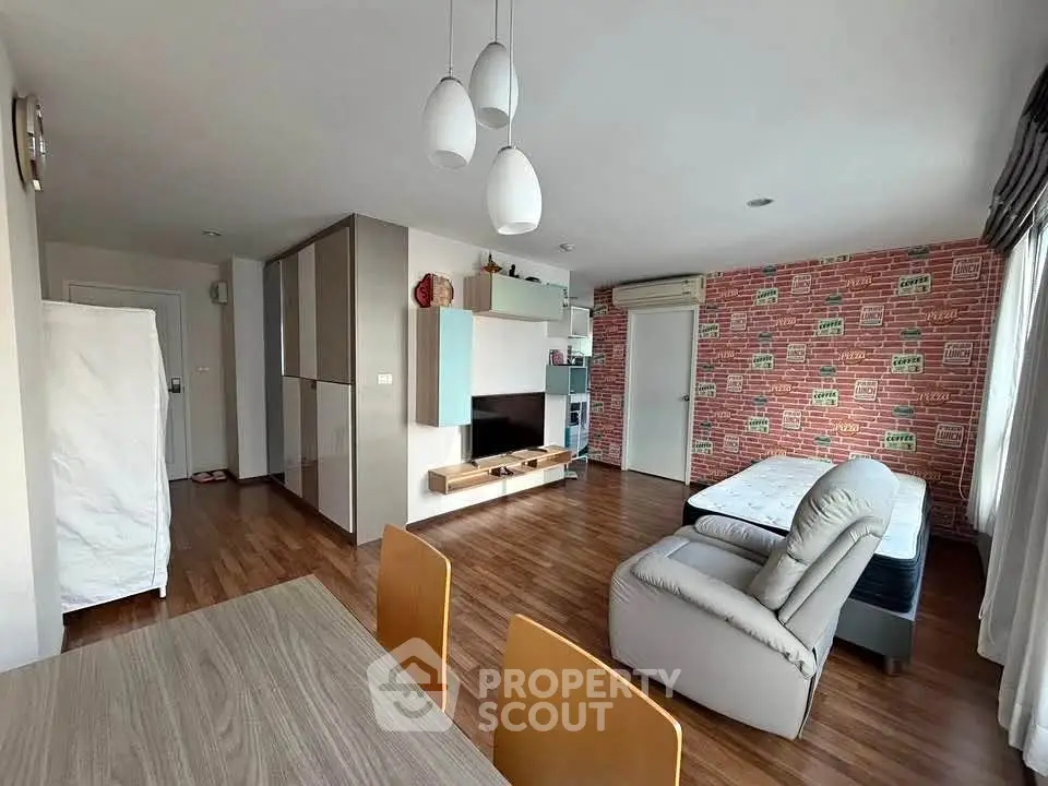 Spacious living room with modern decor and wooden flooring, featuring a cozy sofa and stylish lighting.
