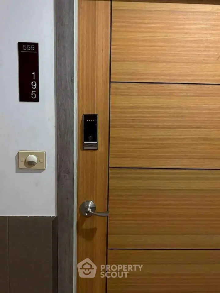 Modern wooden apartment door with electronic lock and room number signage.
