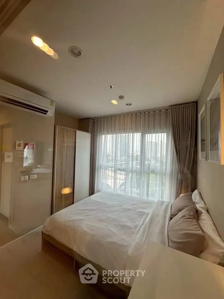 Cozy bedroom with large window and modern furnishings in a stylish apartment.