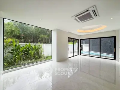 Spacious modern living room with large windows and pool view, perfect for luxury living.