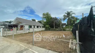 Vacant land plot in a residential neighborhood with modern houses and lush greenery.