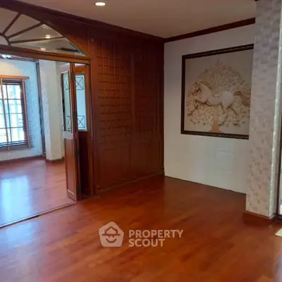 Elegant hardwood-floored room with decorative wall panel and large windows, perfect for a stylish living space.