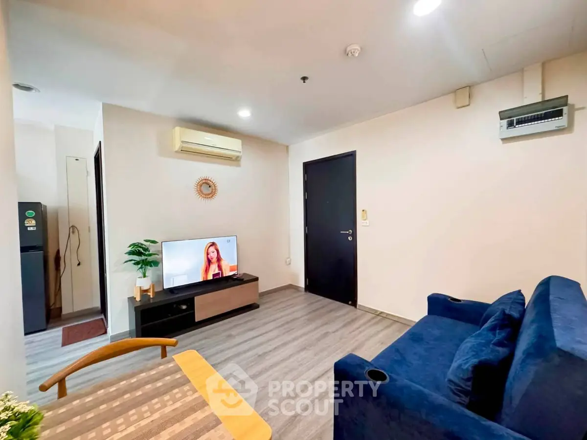 Modern living room with stylish furniture and wall-mounted TV in a cozy apartment.