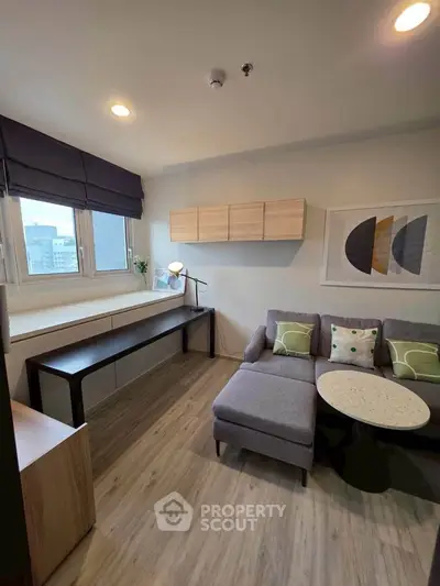 Modern living room with stylish decor and large windows offering city views.