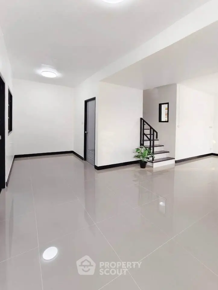 Spacious modern interior with sleek tile flooring and staircase, ideal for contemporary living.