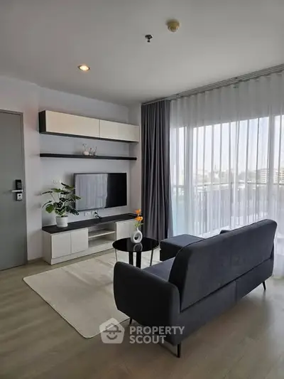 Modern living room with sleek furniture and large window offering natural light