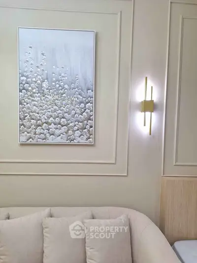 Elegant living room with modern art and stylish lighting, featuring a cozy beige sofa.